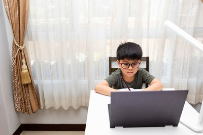 Young woman using mobile phone while sitting on table