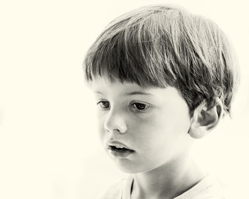 Close-up portrait of boy looking away against white background