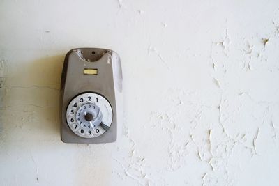 Abandoned rotary phone on weathered wall