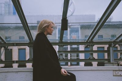 Woman looking through window in city