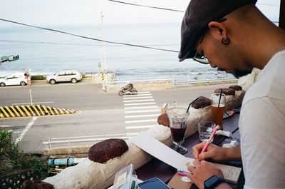 Side view of man using mobile phone while sitting on road