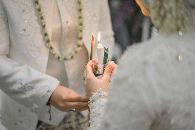 Midsection of bride and groom performing rituals during wedding ceremony