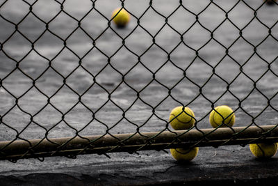 Close-up of tennis balls by chainlink fence