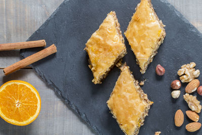 A rectangular slate plate with three lozenges of baklava, cinnamon and orange.