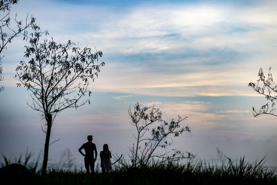 Silhouette people standing on field against sky during sunset