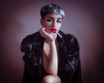 Portrait of beautiful young woman against pink background