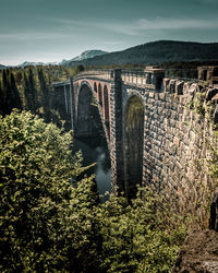 Arch bridge over river against sky