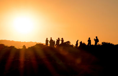 Silhouette people on landscape against sky during sunset