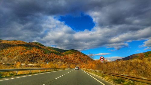 Road leading towards mountains against sky