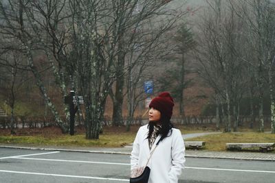 Full length of woman standing on road amidst bare trees