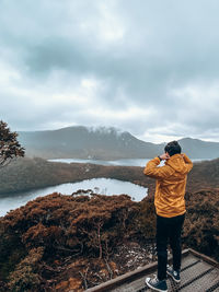 Rear view of man photographing against sky