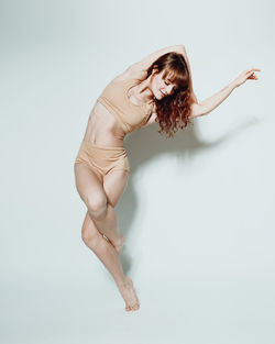 Full length of young woman exercising against white background