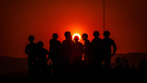 Silhouette army soldiers against sky during sunset