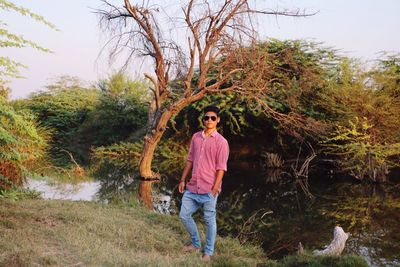 Full length of young man standing at riverbank