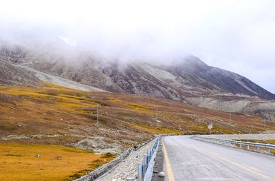 Road leading towards snowcapped mountain against sky