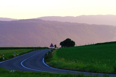 Road amidst field against sky