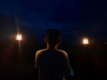 Rear view of silhouette woman standing against sky at night