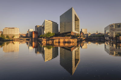 Germany, hamburg, office buildings reflecting in elbe river at dusk