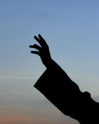 Cropped image of silhouette hand against clear sky