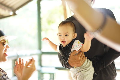 Cheerful mother looking at baby girl held by father