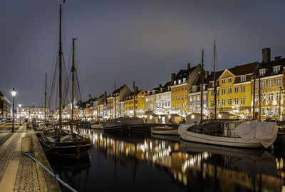 Sailboats moored at harbor against sky at night