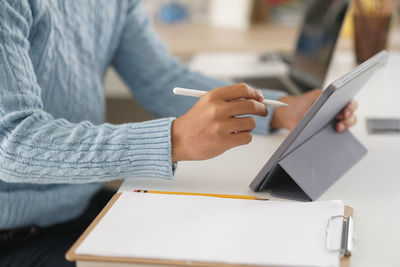 Midsection of man using mobile phone while sitting on table