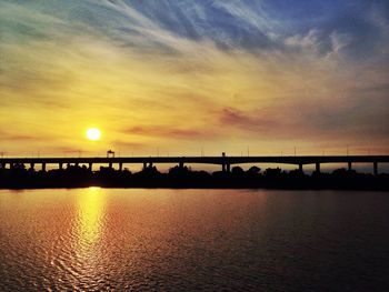 Silhouette of bridge over sea during sunset