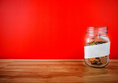 Close-up of glass jar on table against wall