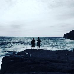 Silhouette people on beach against sky