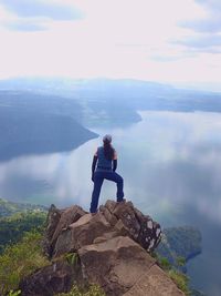 Man standing on rock looking at mountain against sky