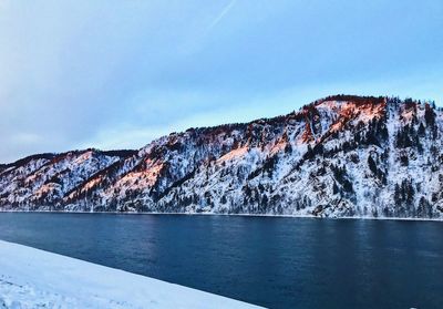 Scenic view of snowcapped mountains by sea against sky