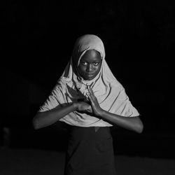 Portrait of girl standing against black background