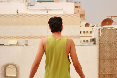 Rear view of man standing against building in city