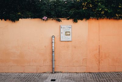 Meter box on orange wall against trees