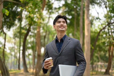 Portrait of young man standing against trees