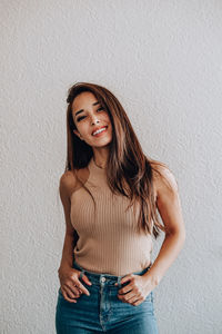 Portrait of a smiling young woman standing against wall