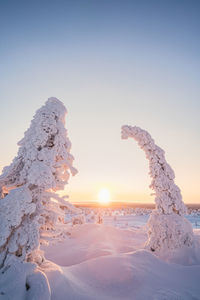 Snow covered land against clear sky during sunset