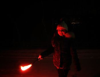 Full length of man standing against illuminated light at night