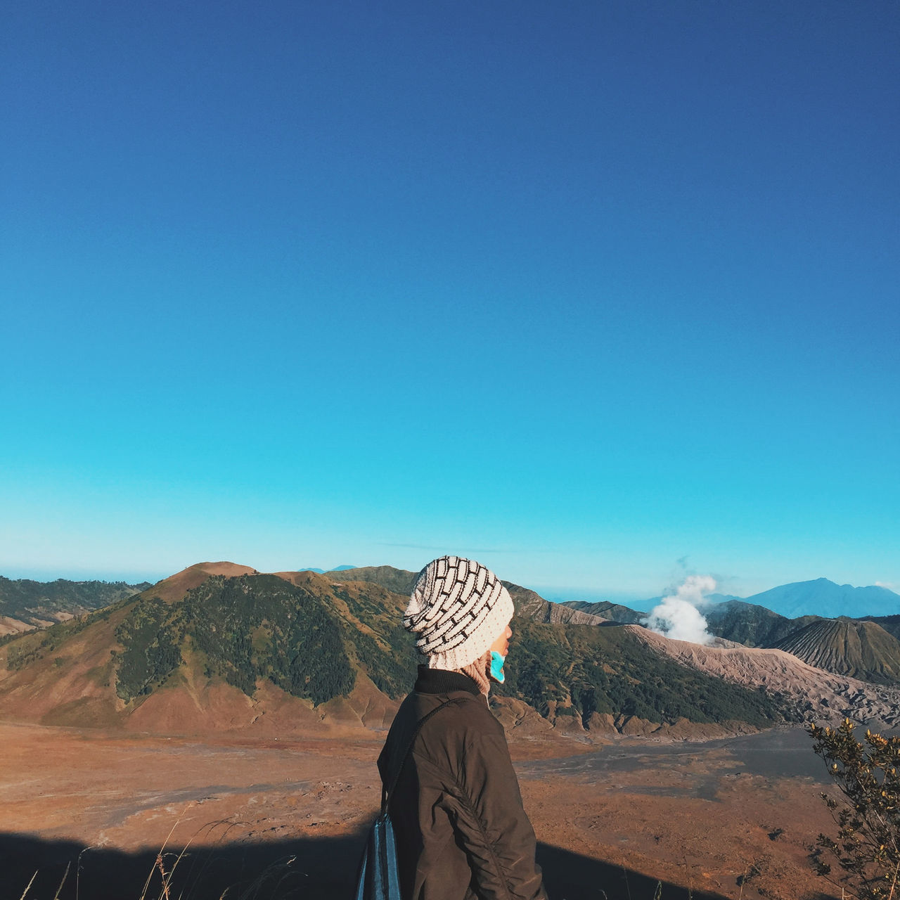 real people, mountain, scenics - nature, sky, copy space, leisure activity, lifestyles, beauty in nature, nature, rear view, clear sky, one person, blue, non-urban scene, environment, clothing, tranquility, landscape, day, mountain range, outdoors, looking at view, climate, arid climate