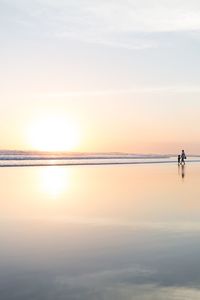 Silhouette man standing on beach against sky during sunset