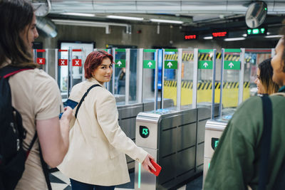 Portrait of young female student looking over shoulder at subway station