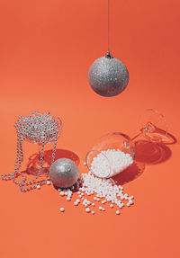 New year shiny decorations and glasses on orange background. minimal celebration concept.