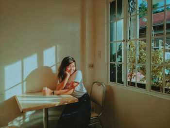 Young woman sitting on table at home