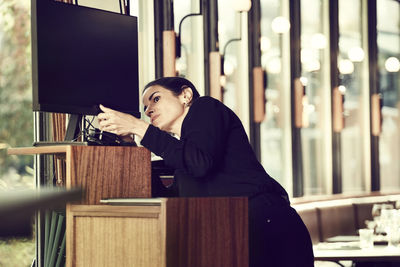 Female owner adjusting computer monitor in cafe