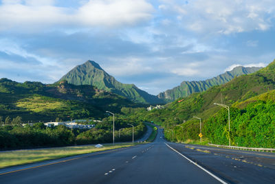 Road by mountains against sky