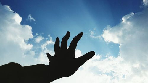 Low angle view of silhouette hand against sky