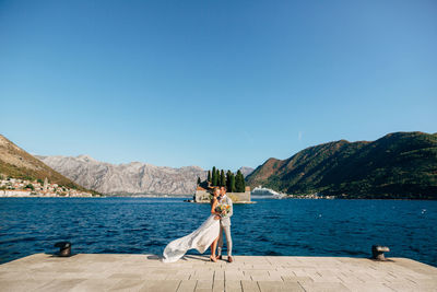 Full length of couple embracing while standing against lake