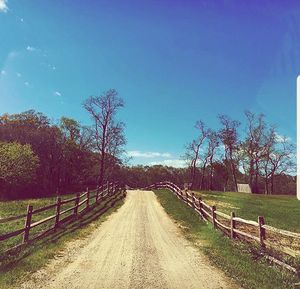 Road amidst agricultural field against sky