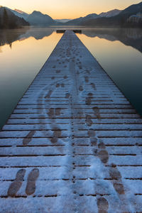 Beautiful wooden jetty with foot prints in the snow, morning light