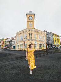 Rear view of woman standing against buildings in city